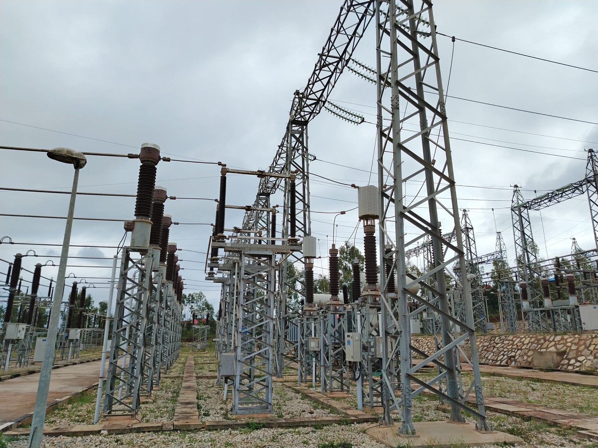 High-voltage electrical substation infrastructure set against a cloudy sky, with green vegetation and trees visible in the background, highlighting a rural or semi-rural landscape in Eastern Ethiopia.