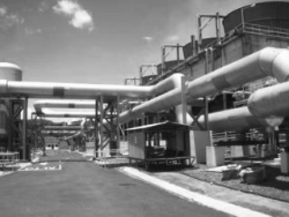 Black and white photo of an industrial facility with insulated pipelines supported by metal structures.