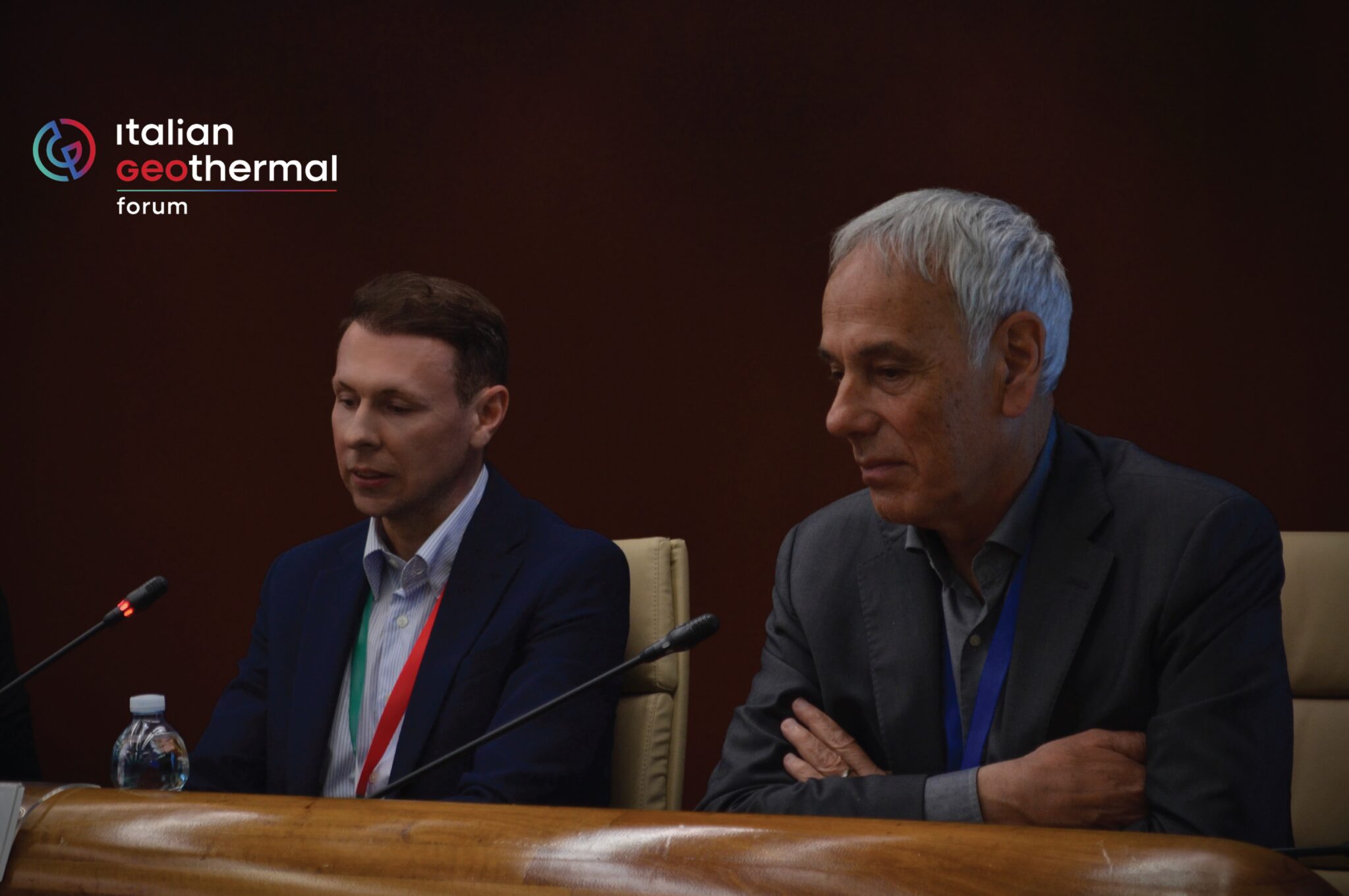 Two men seated at a conference panel during the Italian Geothermal Forum